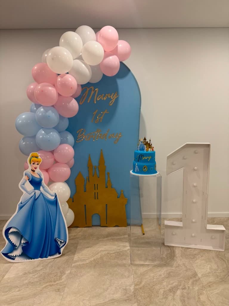 Cinderella-themed first birthday with arch backdrop, balloon garland, cutout, and light number